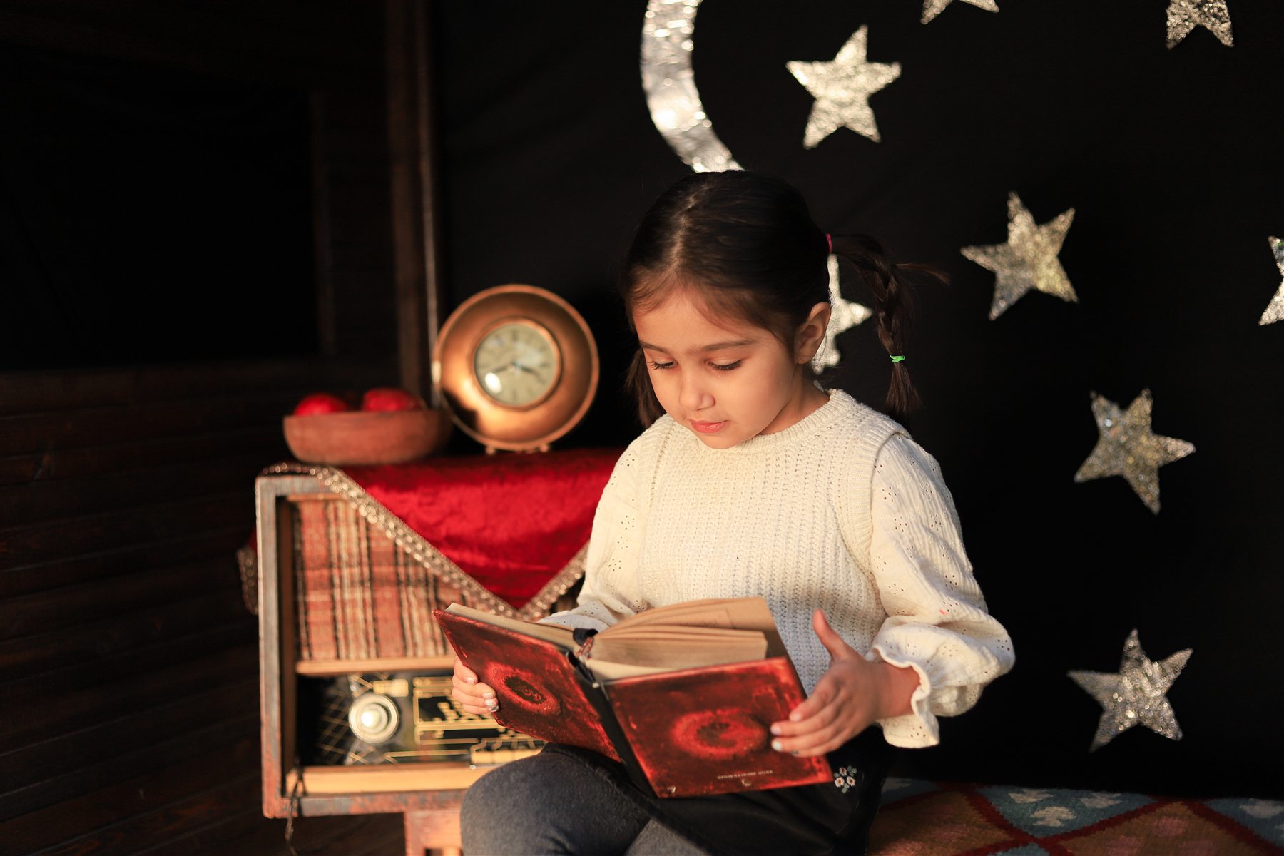 کودک در حال خواندن کتاب در فضای شب یلدا