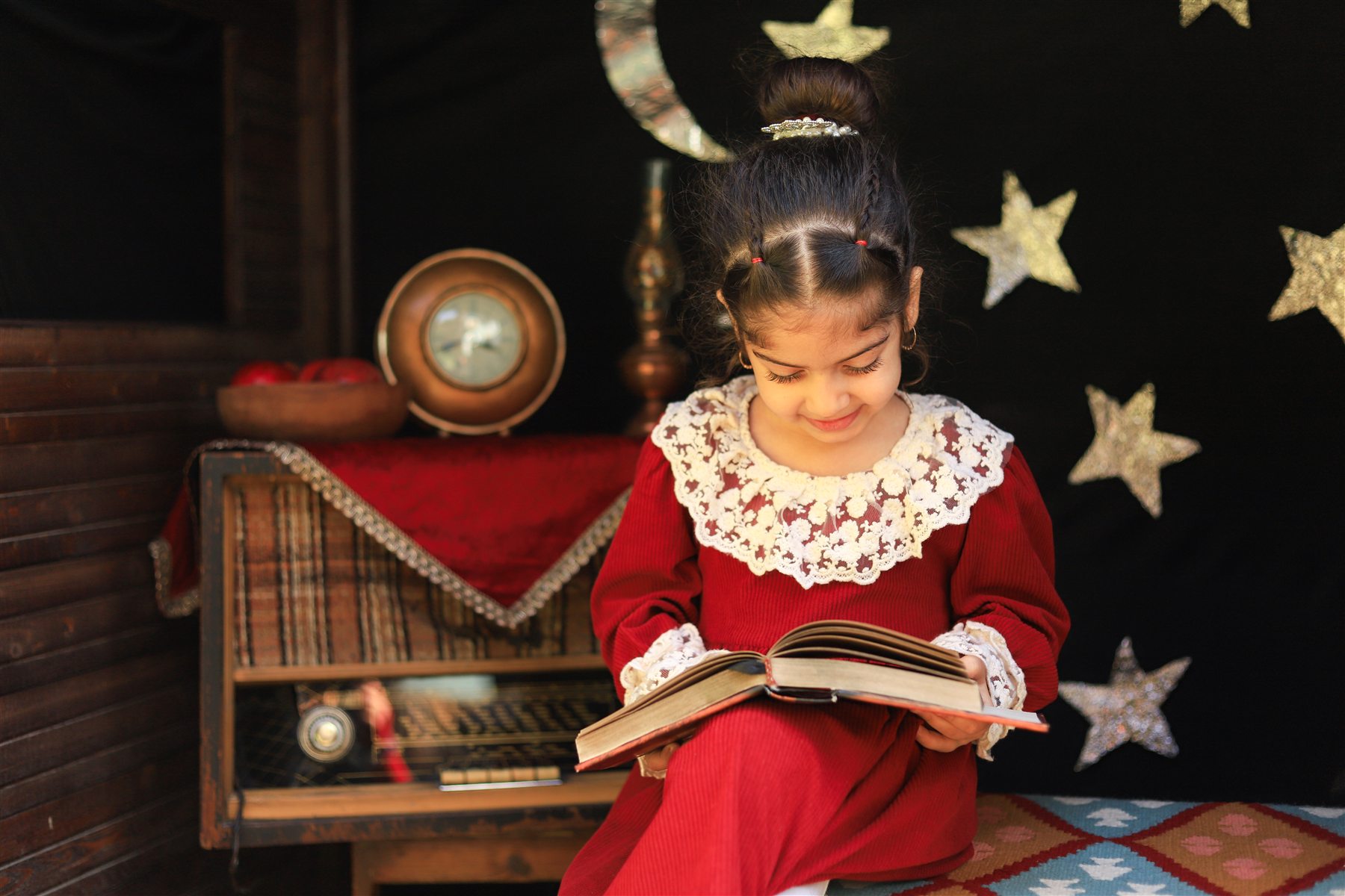 کودک در حال ورق زدن کتاب در دکور یلدا